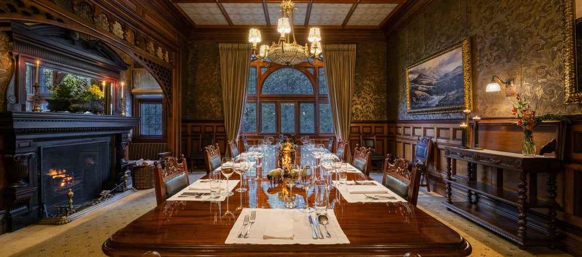 Luxurious dining room with a large wooden table, ornate chandelier, and decorative walls.